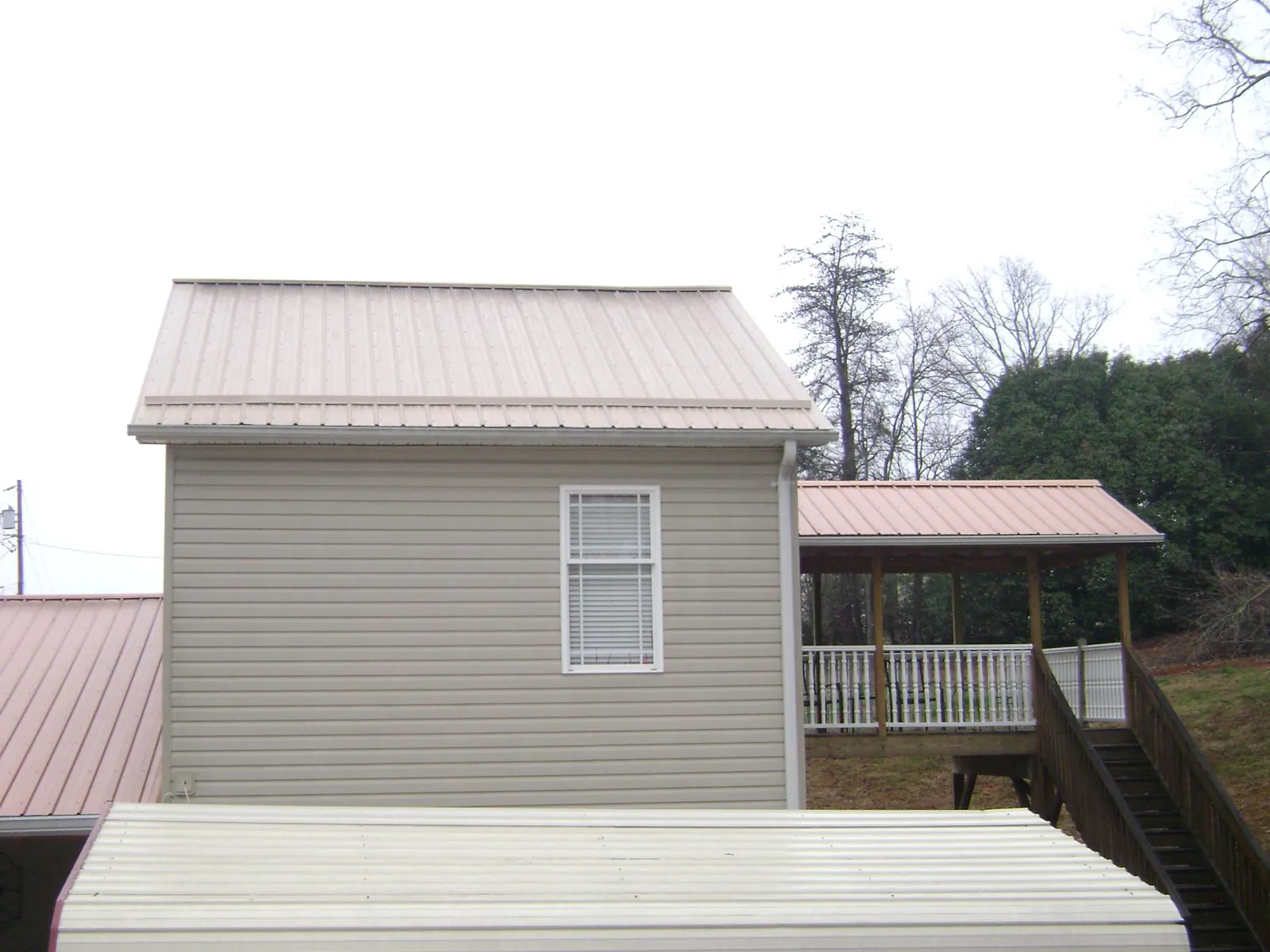 Tan metal roofs on a two story addition and attached porch, from a Roof Replacement job in Hadley